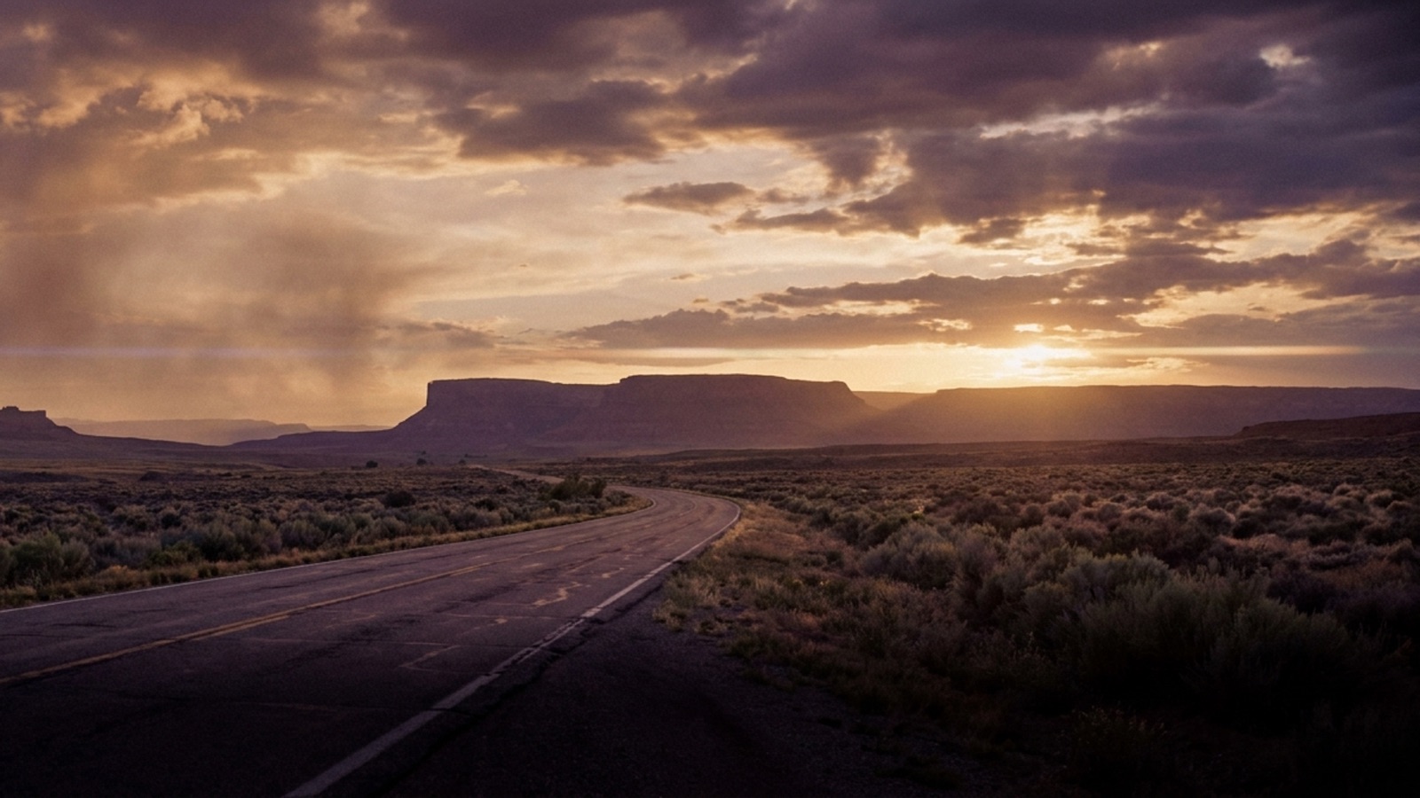 An open desert road toward the mountains at golden hour